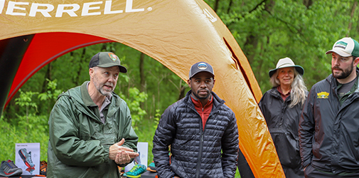 Chima stands next to a tent in the woods