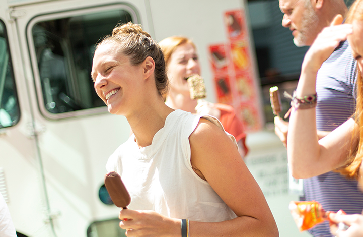 A woman smiles while holding an ice cream bar