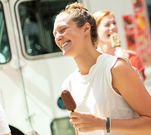 A woman smiles while holding an ice cream bar