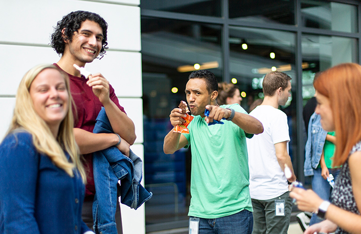 A man points to the camera while holding an ice cream sandwich