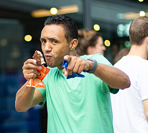 A man points to the camera while holding an ice cream sandwich