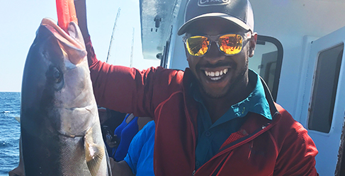 Chima holding a fish on a boat