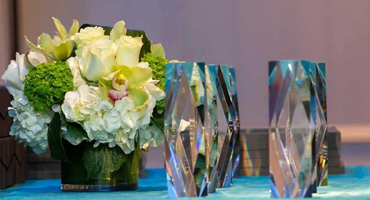 A photo of flowers in a vase next to three crystal reward statues