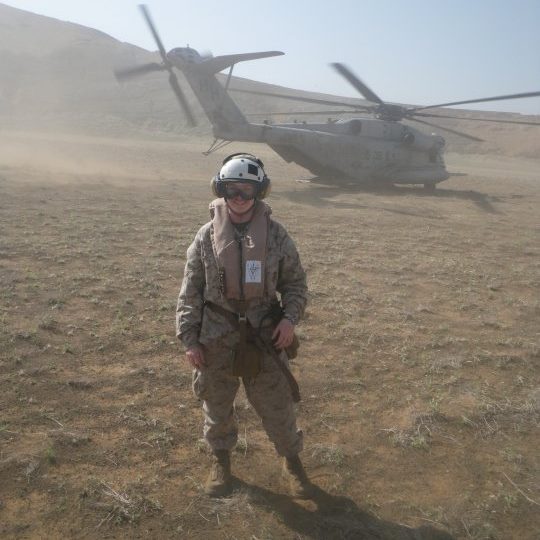 Women in military uniform in front of helicopter