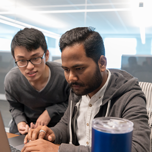 Two Schwab employees working together in office on a computer