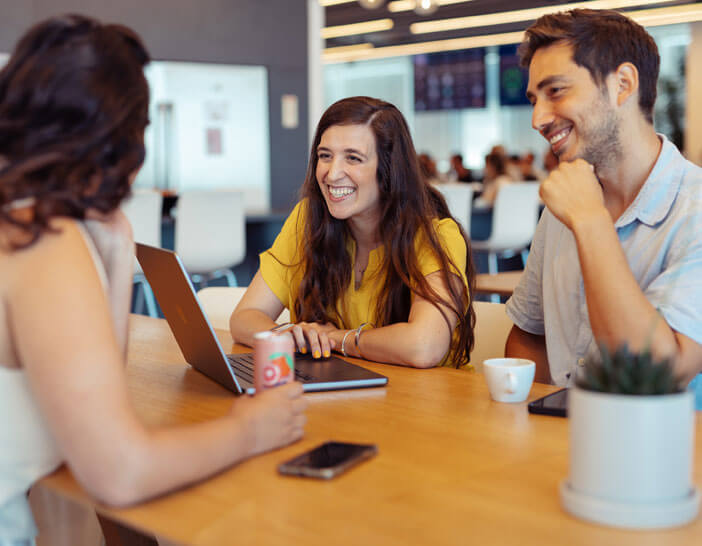 Three employees sitting at a table having a conversation