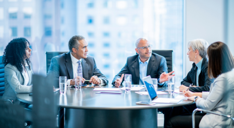 Group around a meeting table discussing sales