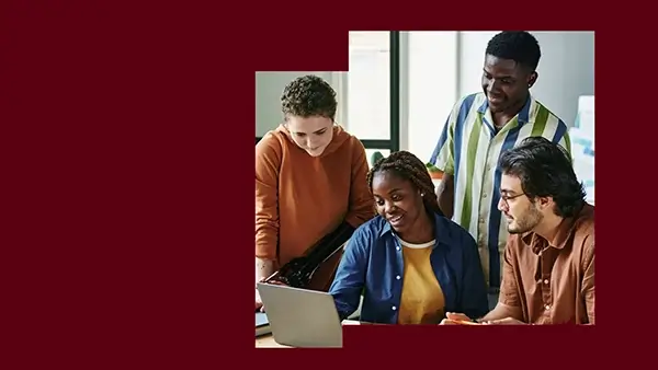 A group of employees working together on the same laptop