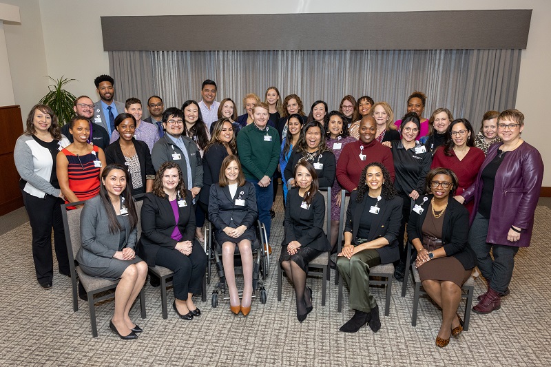 A few dozen leaders from the Northwestern Medicine Champion Network in a meeting room. They are wearing business attire. 