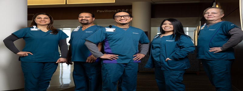 A team of five Northwestern Medicine imaging technologists wearing dark blue medical scrubs pose for a photo.
