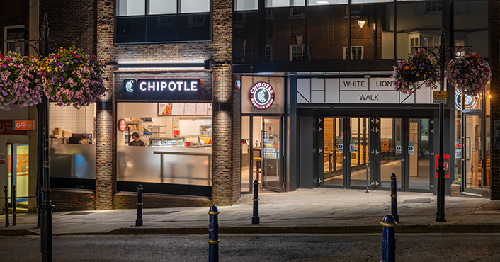 across the street and looking into the storefront of a London Chipotle