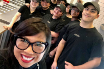 Chipotle Chief People Officer, Marissa Andrada, poses in a restaurant with happy crew members.