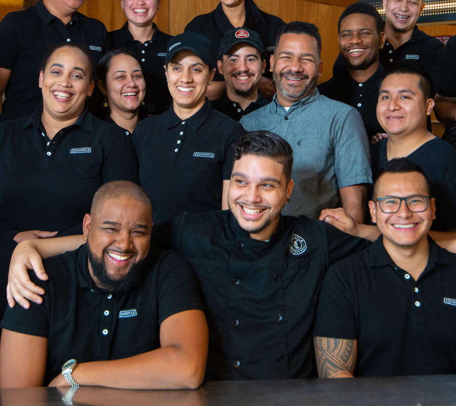 Los miembros del personal de Chipotle se reúnen contentos en el restaurante para tomarse una fotografía grupal.