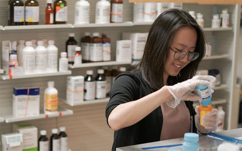 Woman filling a pill bottle in a pharmacy