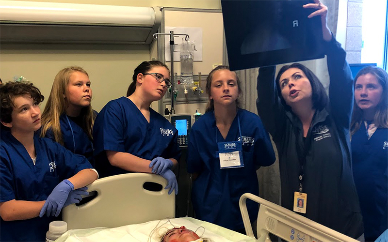 Woman pointing at an x-ray to a group of students