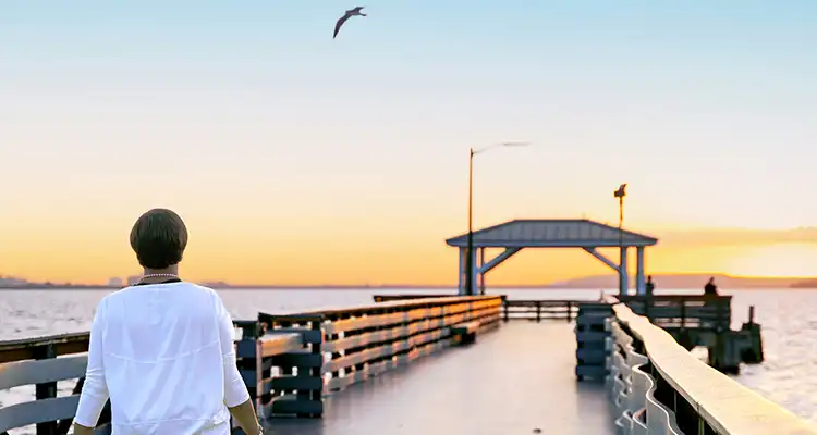 A woman on a pier watching the sunset