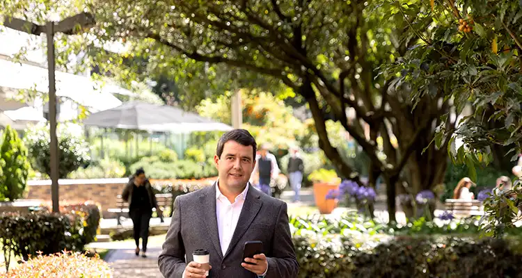 A man searching for jobs on his phone in a park
