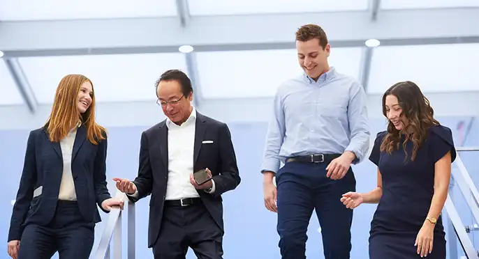 Four professionals walking and interacting in a modern office building