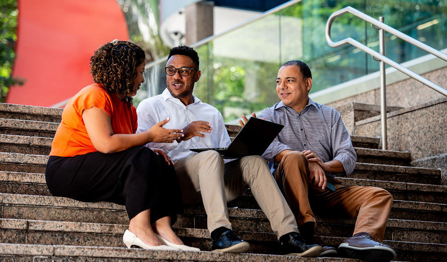 Three colleagues sitting on steps outside the office building