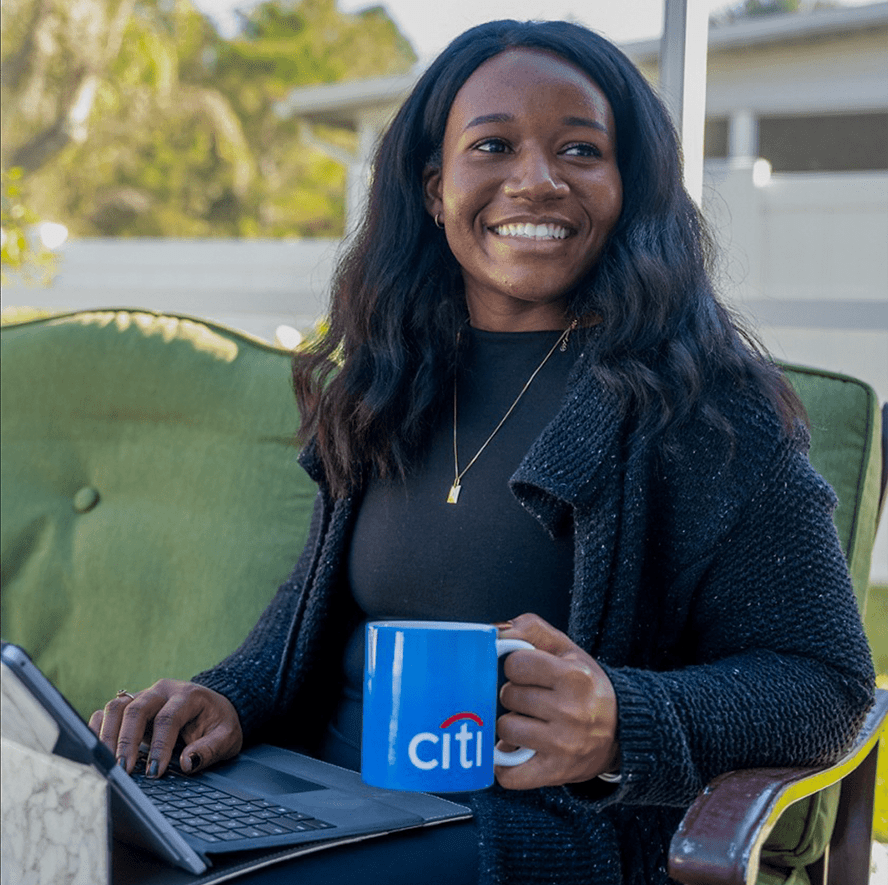 Woman on her laptop while enjoy a cup of coffee from a Citi mug