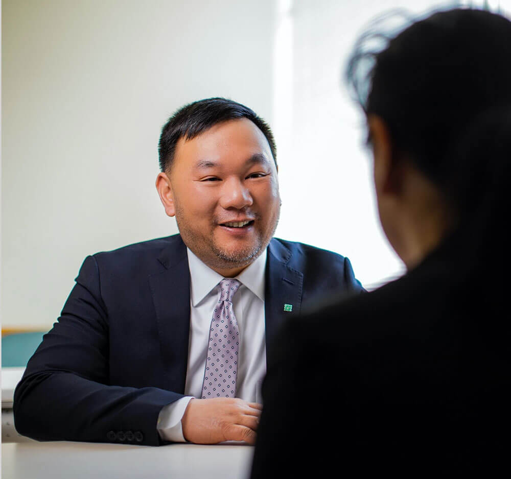 asian male employee in a navy blue suit meeting with a client