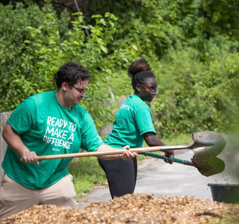 3 smiling employees wearing green Citizens t-shirts while volunteering in a community kitchen