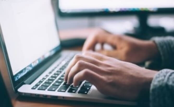 hands typing on a laptop keyboard