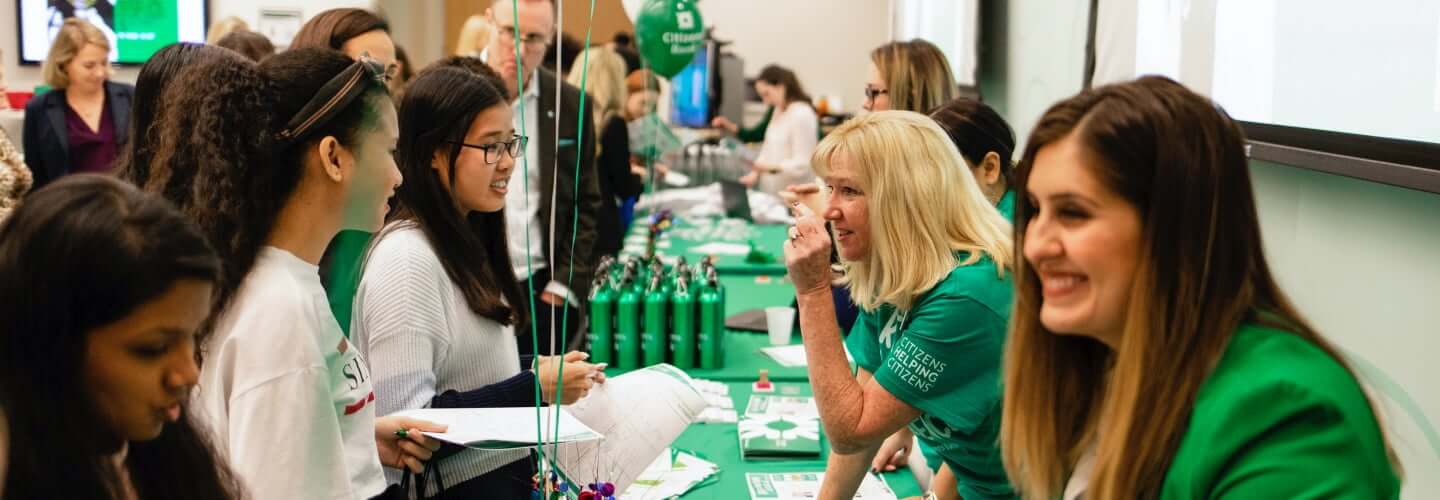 Female employees in Citizens t-shirts speaking with students at a hiring event
