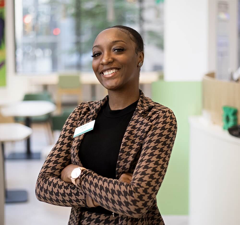 Black female employee in office attire standing in a break room and smiling