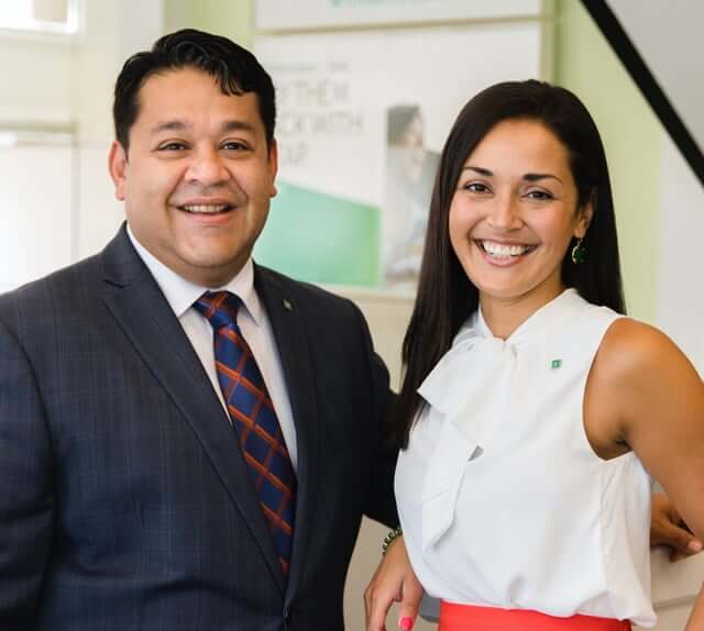 Hispanic American male and female employee, each wearing business attire and smiling