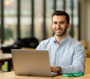 young female waving and smiling in front of a laptop