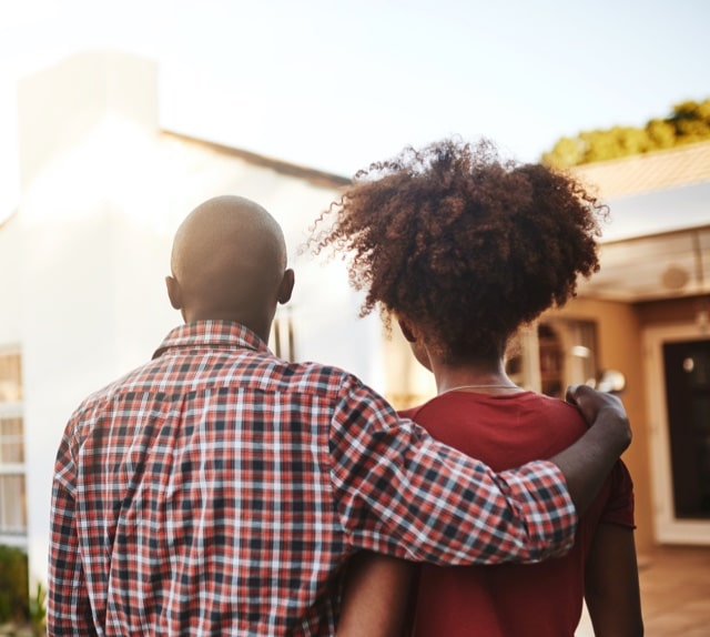 husband and wife looking up at a newly purchased house