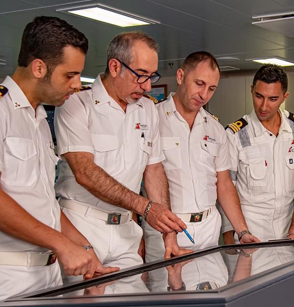 four ship officers looking at a computer screen