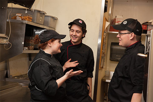 Two cooks talking with kitchen manager