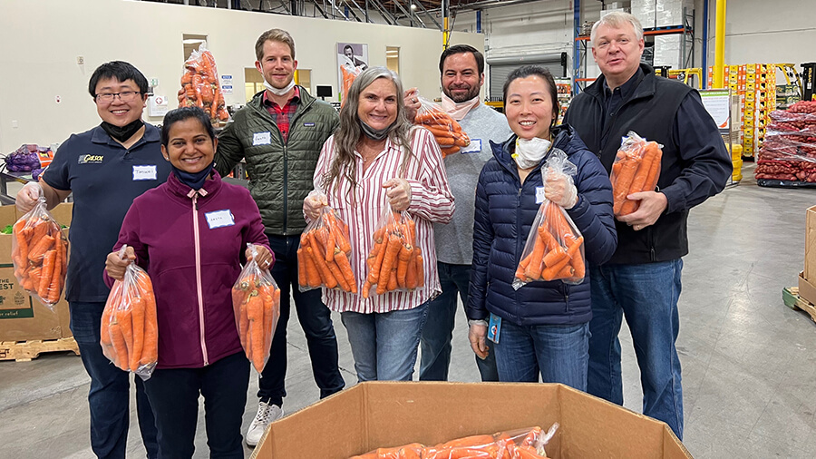 A group of PG&E volunteers are standing together and holding food to be donated.