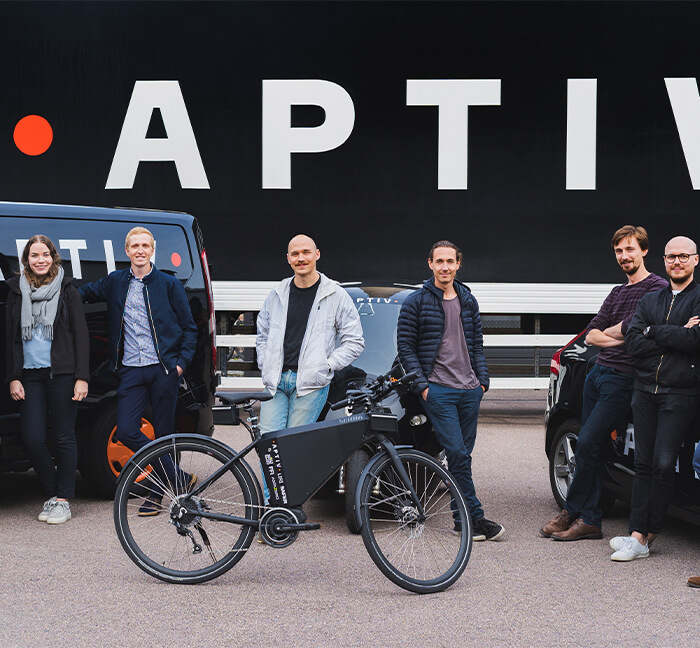 Group of Aptiv Employees standing outside in front of some vehicles