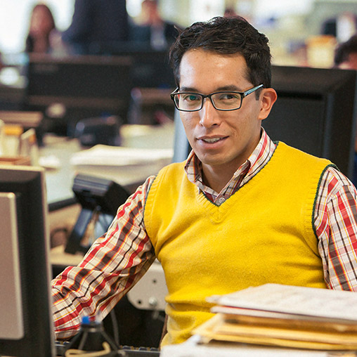 A person wearing yellow sweater is sitting in front of computer system