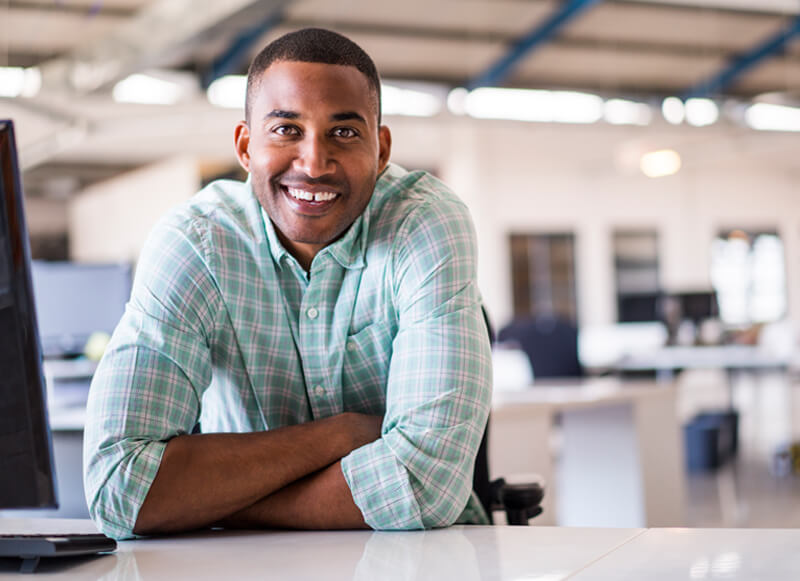 black male BioLife employee in office attire sitting at desk and smiling
