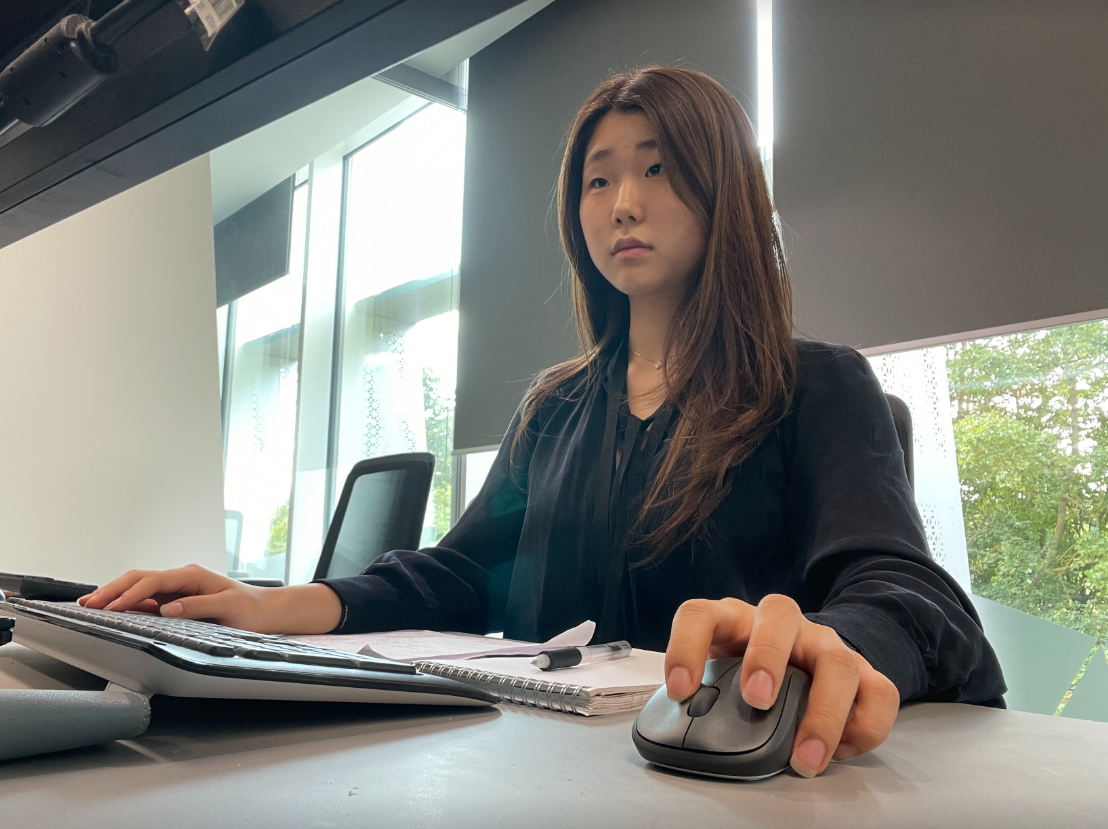 Hyo, an Arm engineering intern, working at her computer with notes at her desk
