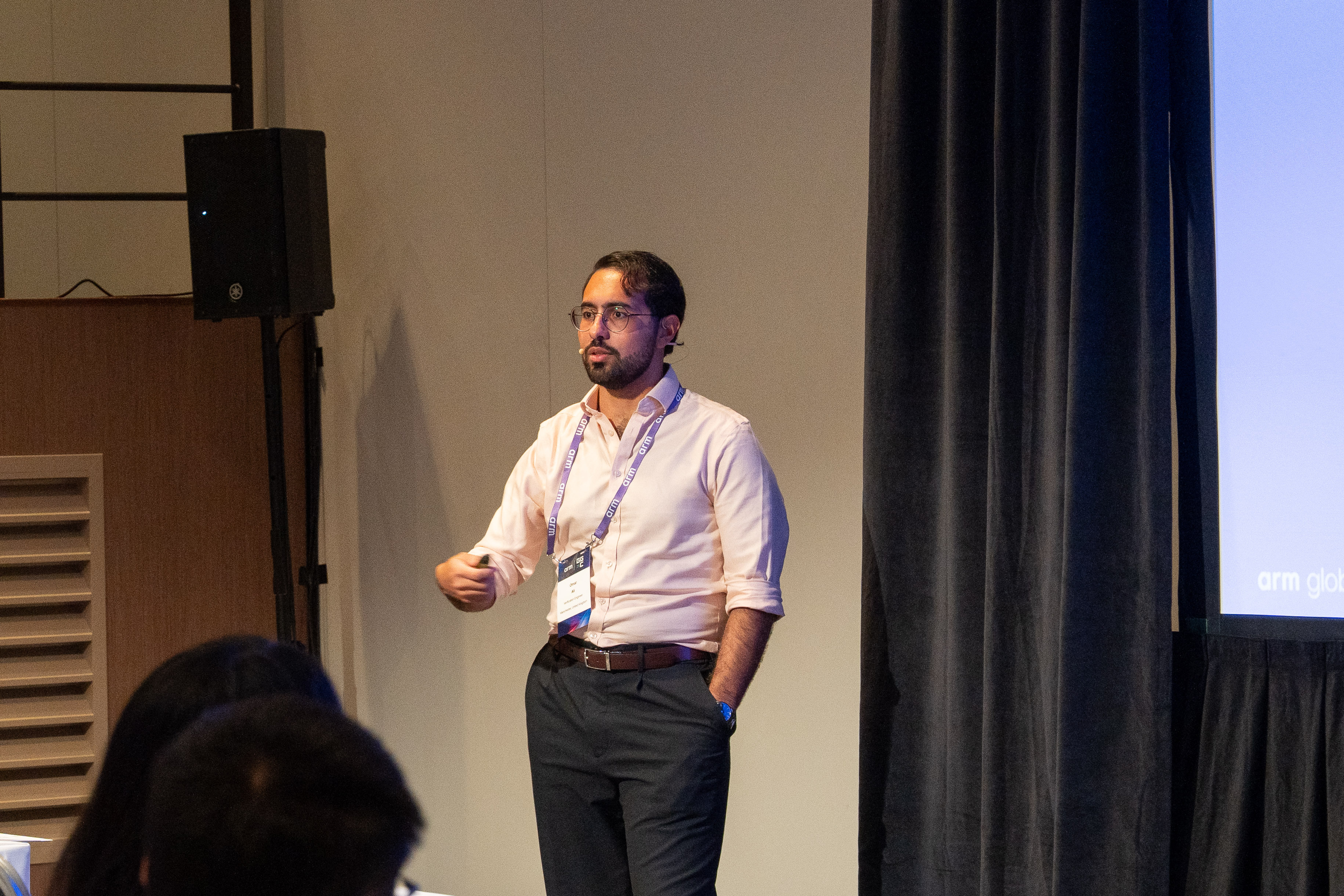 Omar presenting on stage to an audience during an event.