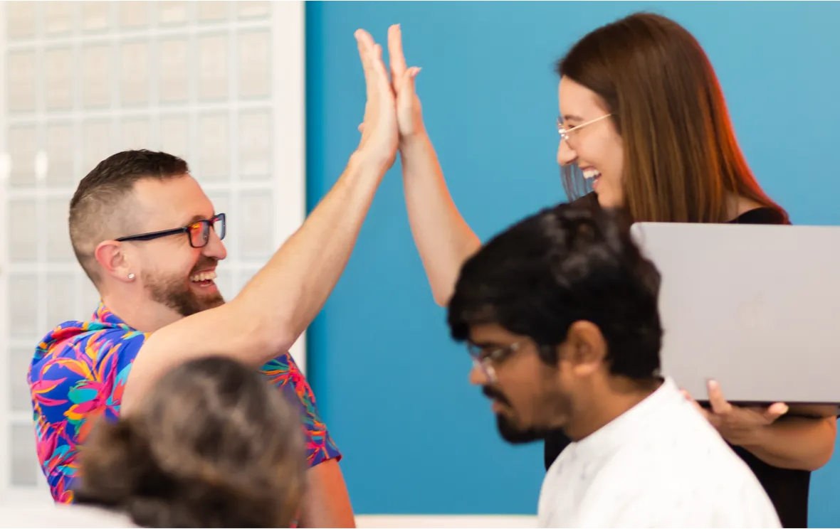 Two coworkers high-fiving and smiling