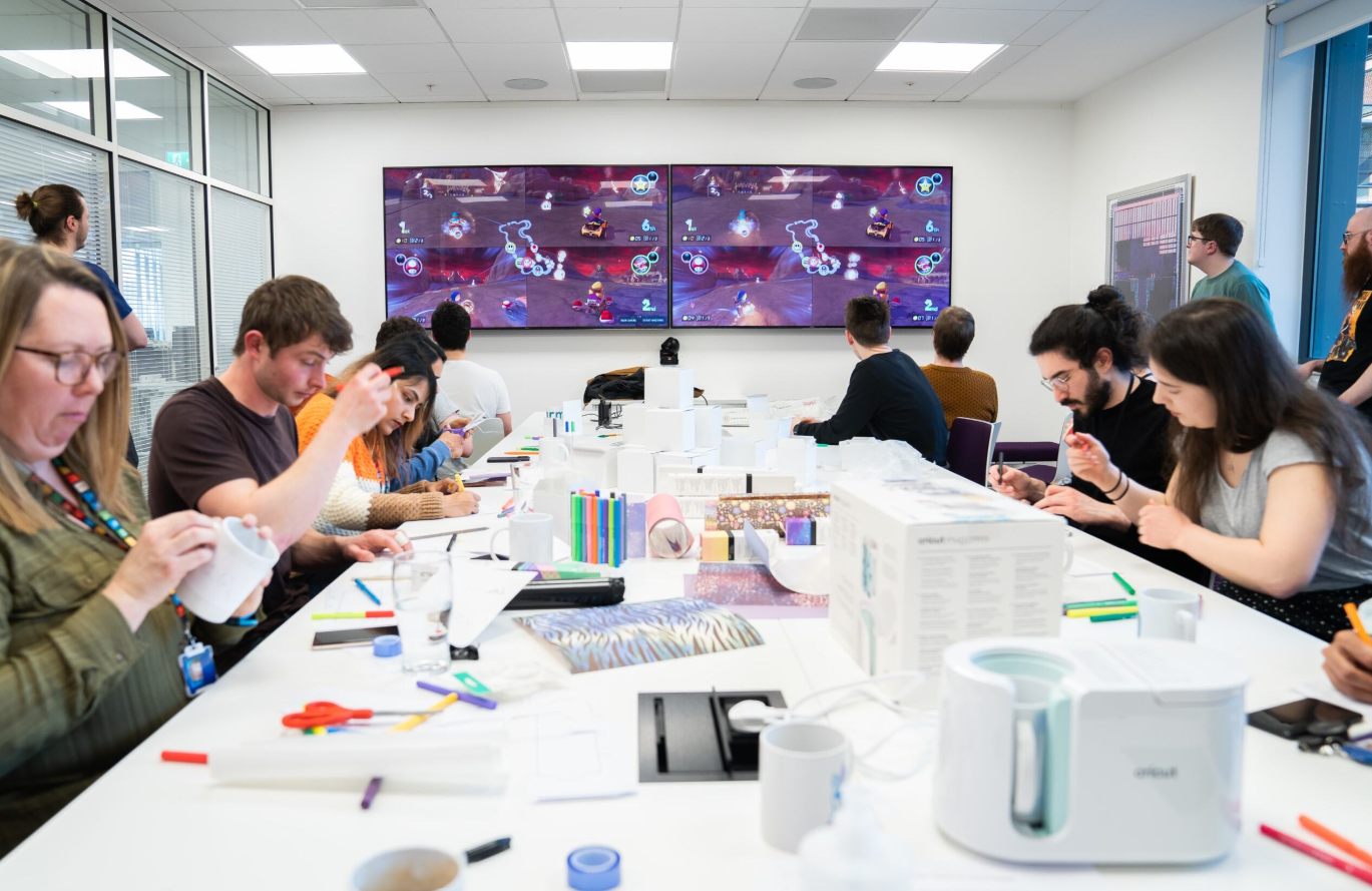 People decorating mugs while a game plays.