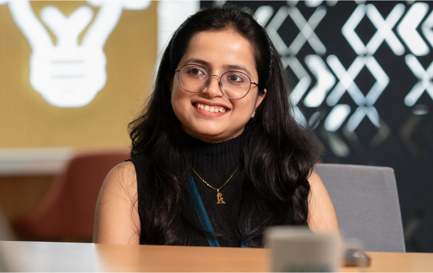 Smiling woman with glasses in an office.