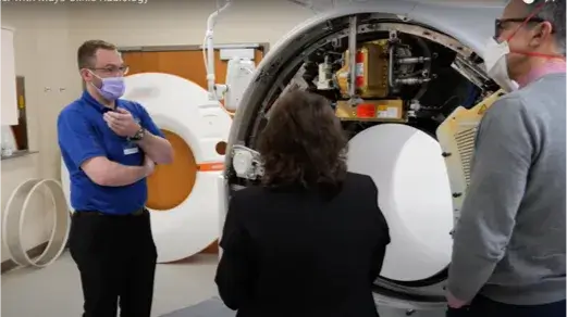 Employee speaking to others in front of equipment (Video)