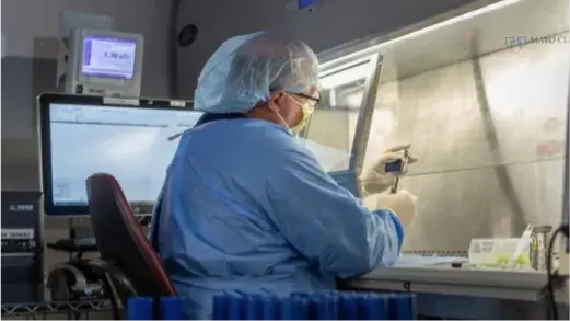A Nuclear Medicine Technologist looking at a vial with a hairnet on their head (Video)