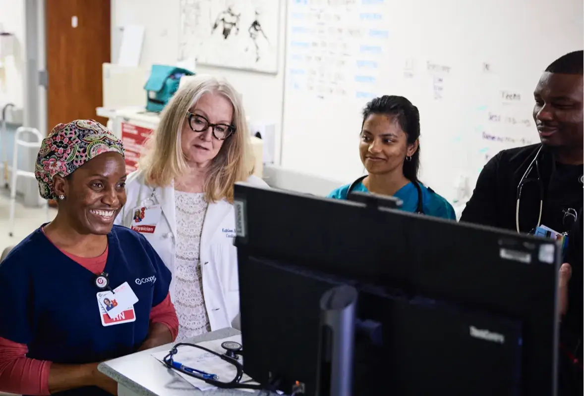 Registered nurses standing around a computer discussing work