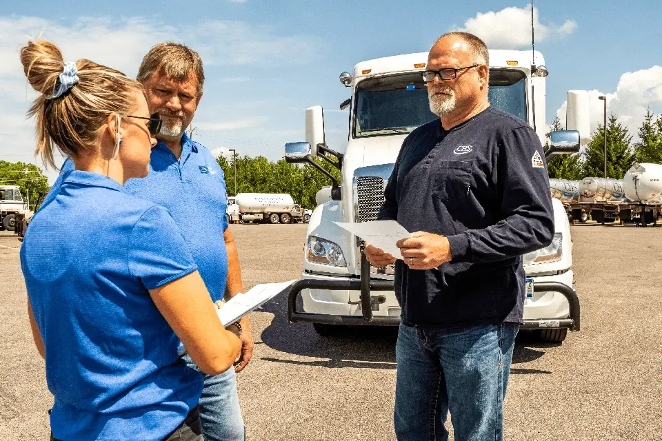 Three employees talking in front of a semi truck