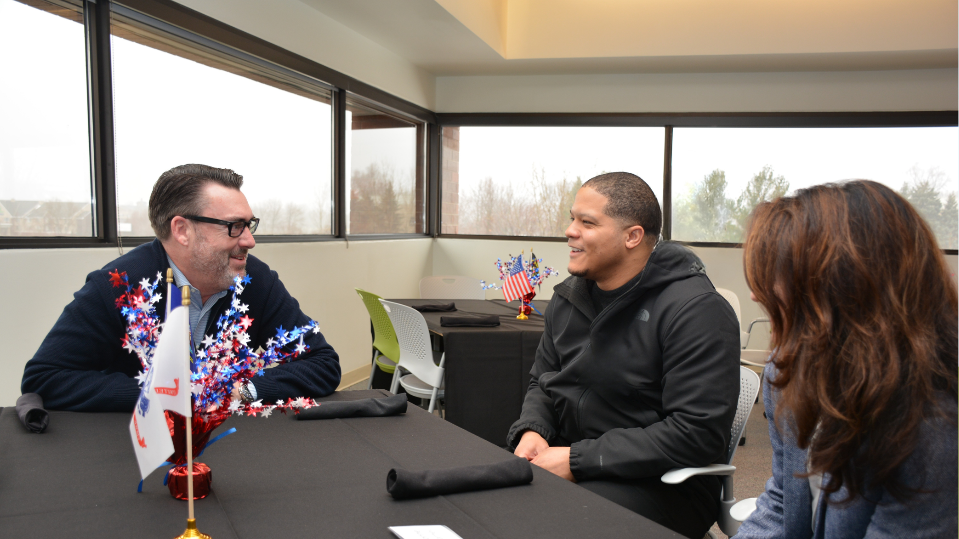 Three people talking around a table.