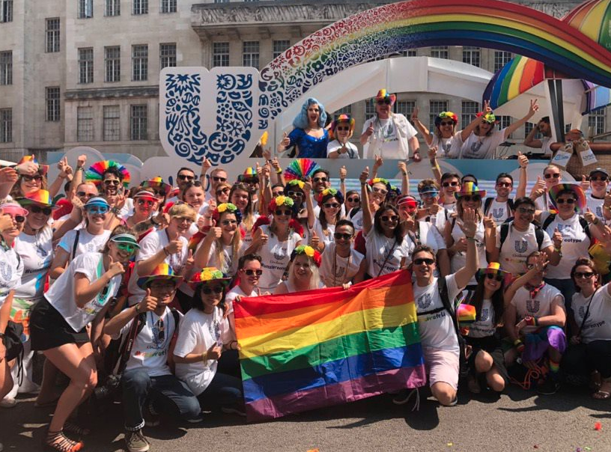 A group of Unilever employees wearing LGBTQ+ clothes and holding a flag