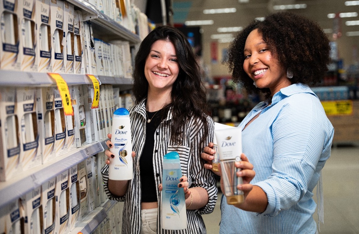 duas jovens talentos, em uma gôndola de produtos, segurando produtos Dove.